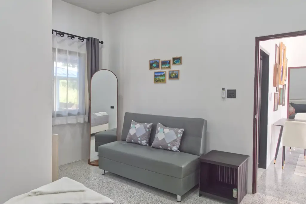 Bedroom 2 at Baan Bahng Can Do Krabi homestay showing sofa bed, full-length mirror, Krabi island photo prints, and open door through to shared dining area